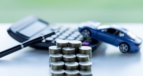 Toy car on calculator with stacks of coins